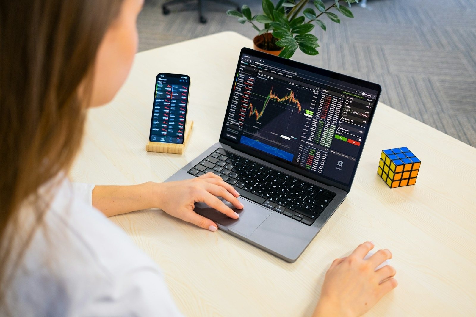 Investor reviewing stock charts on a laptop and phone